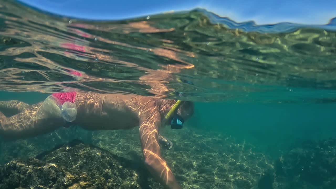 얕은 물에서 마스크와 스노클링 낚시 성게를 가진 남자의 절반 수중보기