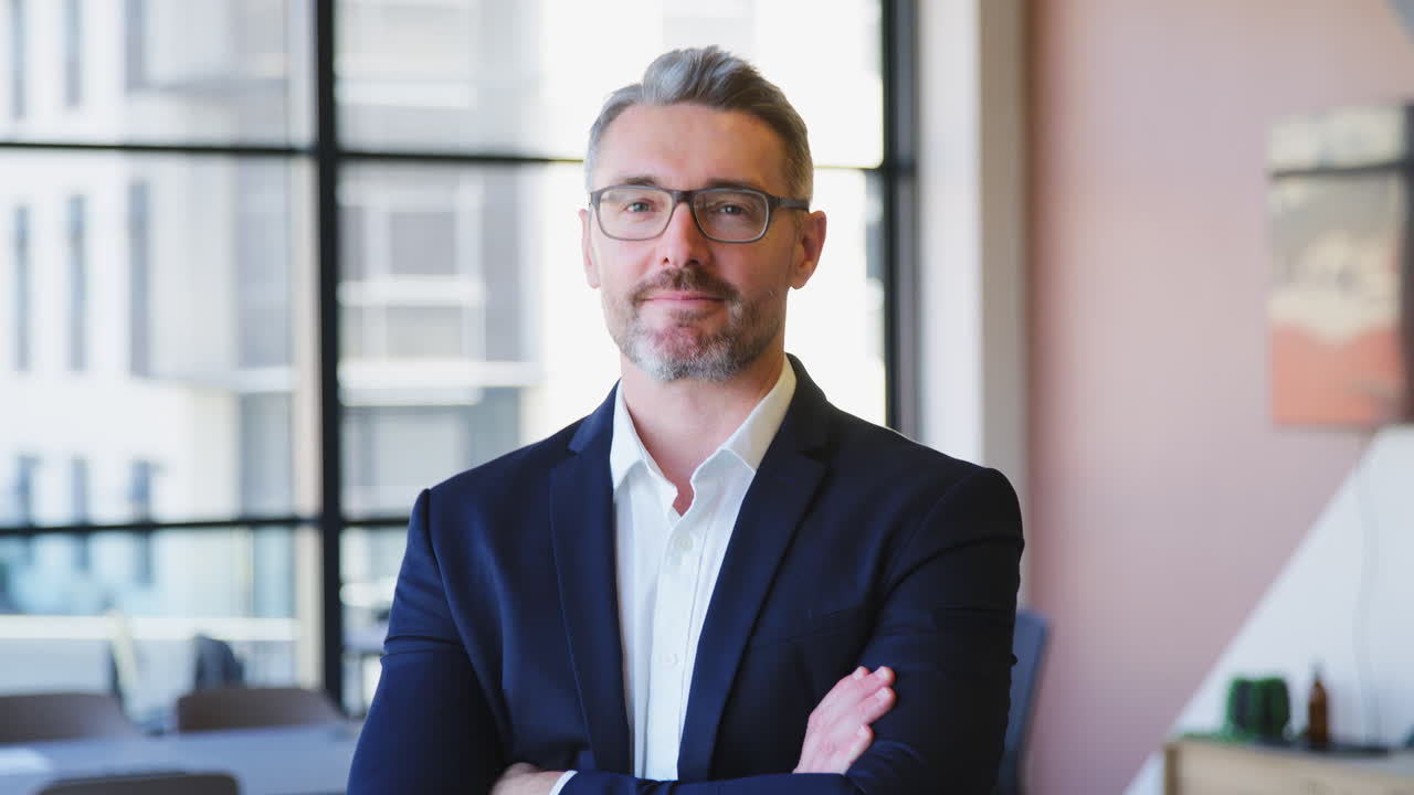 Portrait Of Serious Mature Businessman Wearing Glasses  Standing In Empty Office