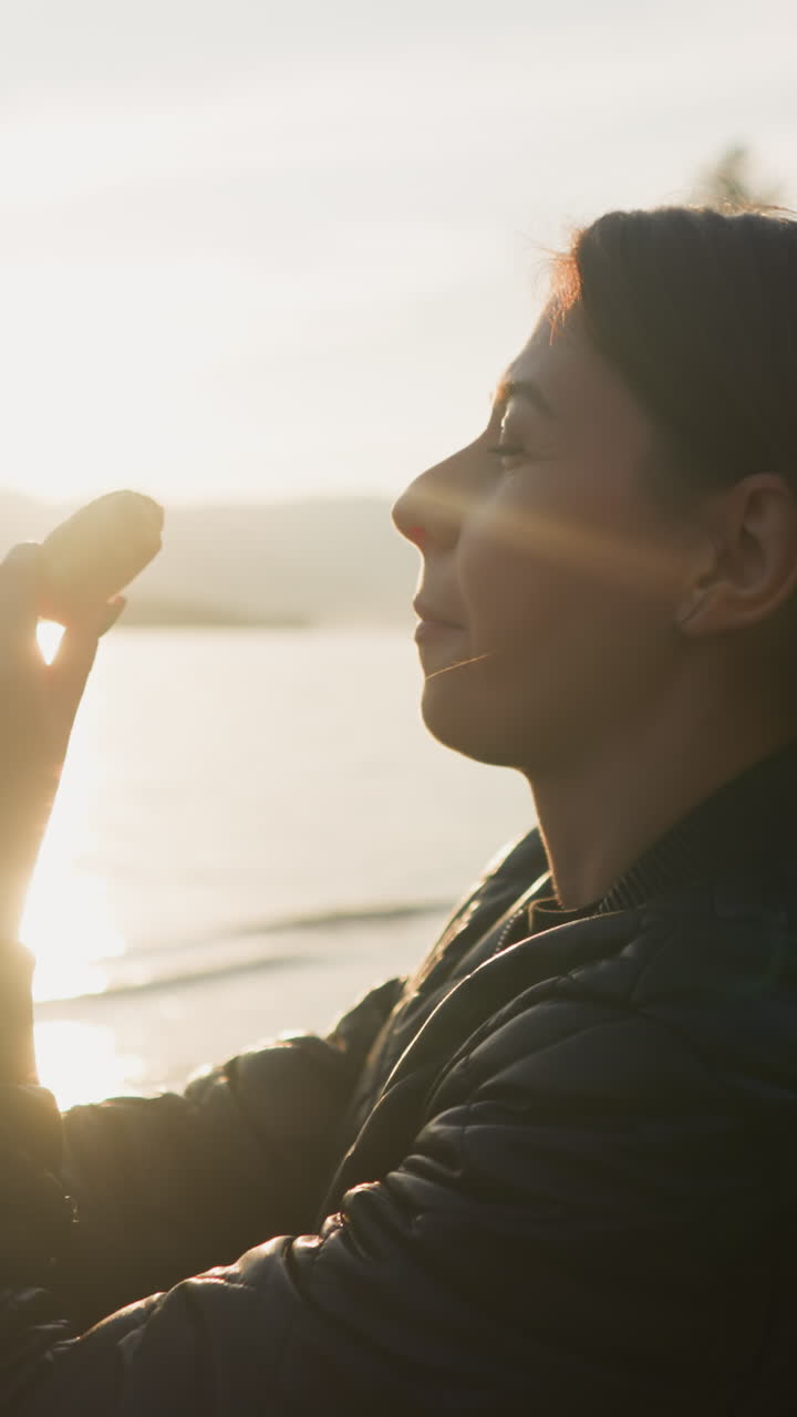 mujer comiendo naranja en la orilla del lago al atardecer. dama sonriente disfruta de pasar tiempo en picnic con su pareja. viendo la belleza de la naturaleza al atardecher de la noche de otoño