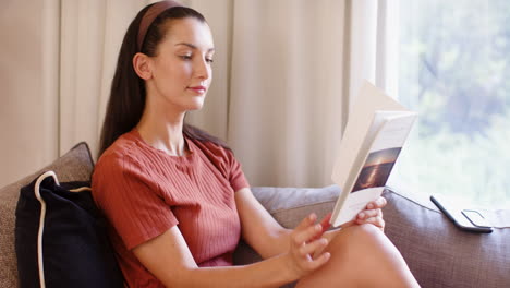 woman relaxing on sofa reading book, enjoying peaceful afternoon at home