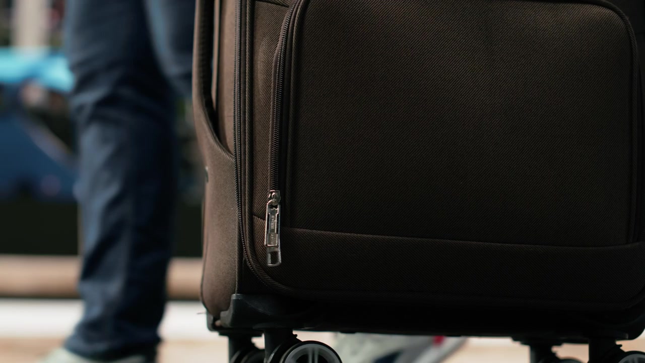 Primo piano di un viaggiatore con trolley in stazione degli autobus