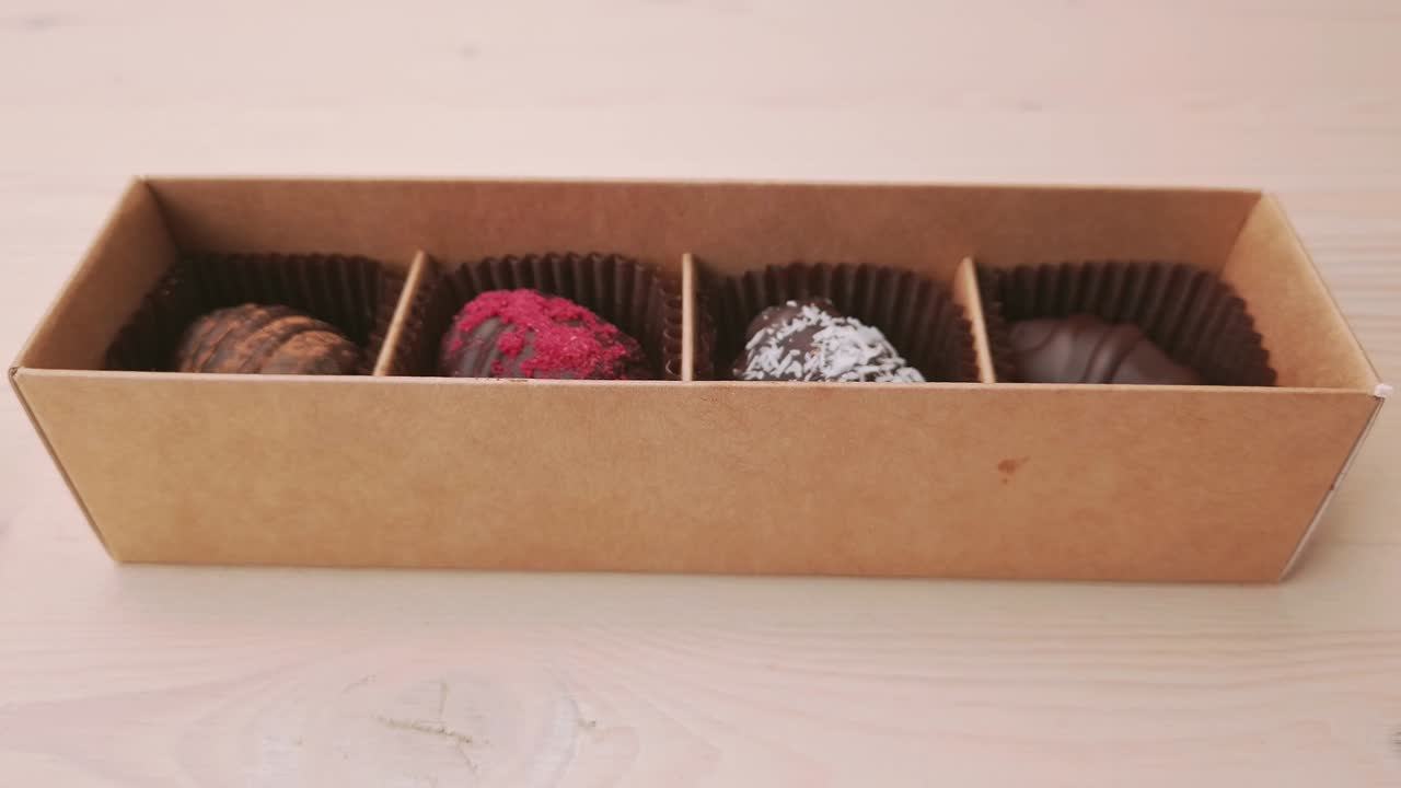fabricación de cajas de regalos de caramelos de chocolate movimiento de cámara de primer plano extremo. chocolates variados confitería en fondo blanco cámara lenta, deslizador