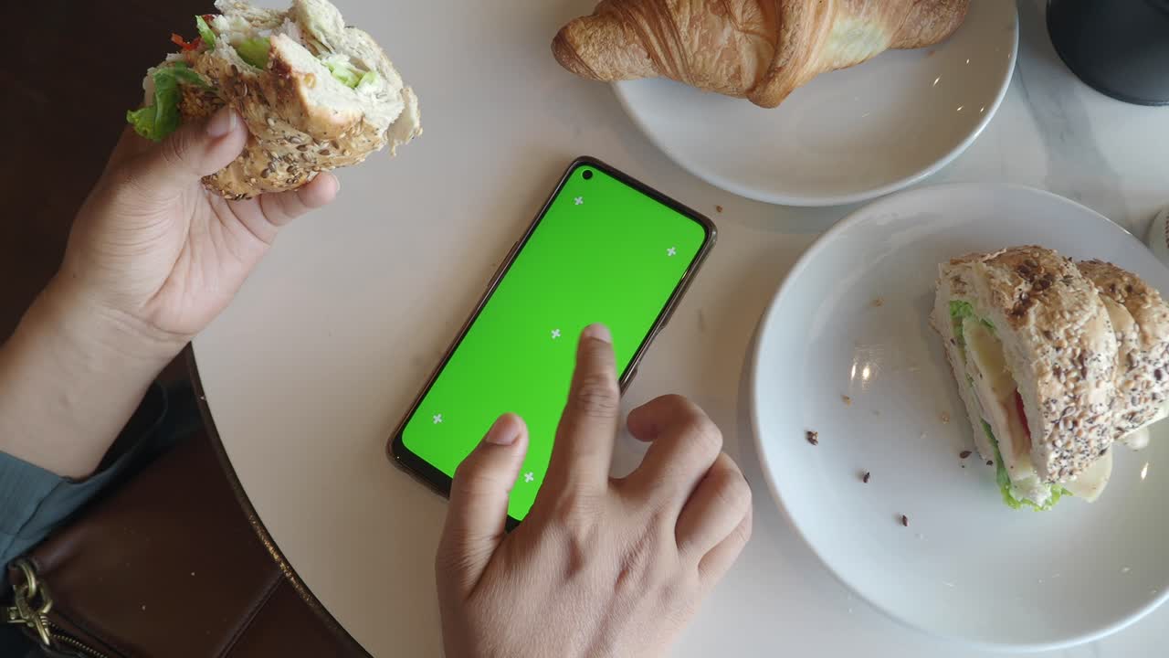 persona comiendo y usando el teléfono en una cafetería