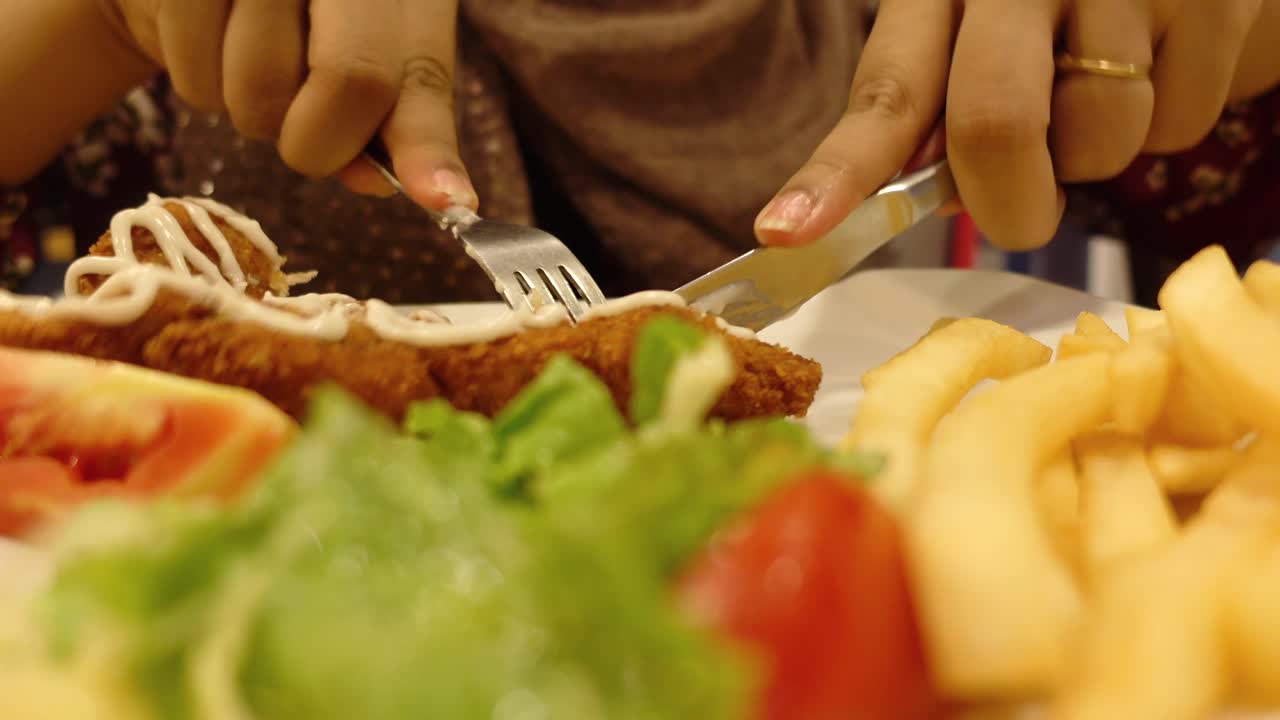 mujer comiendo un plato de pollo frito con papas fritas y ensalada