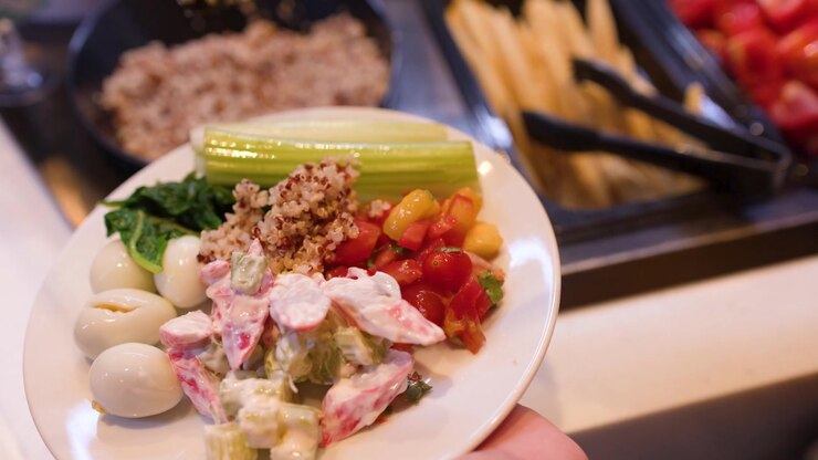 En person tilføjer en skefuld quinoa til en tallerken fyldt med æg og grøntsager.