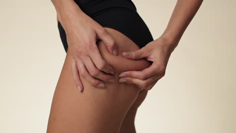 unrecognizable woman touching and pressing skin on her hip.