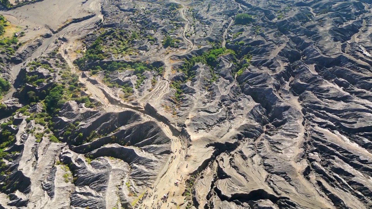 インドネシア、ジャワ島のブロモ火山周辺の溶岩流地形をハイキングする観光客を、高角度からドローンで追跡撮影した4K 30FPS映像
