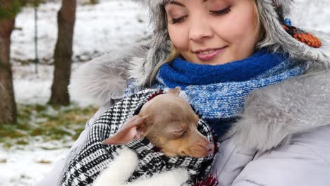 mujer jugando con su pequeño perro fuera del invierno
