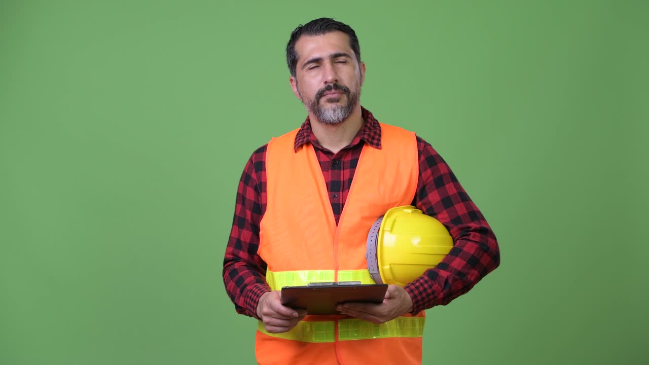 Handsome Persian bearded man construction worker reading clipboard