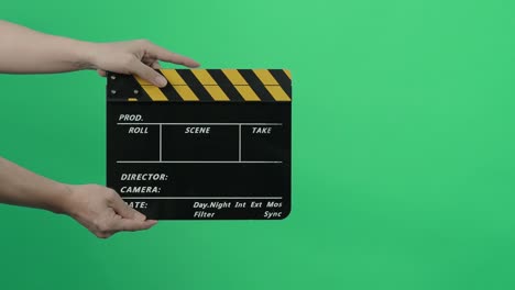 film slate or movie clapperboard with blue green screen background. film crew man hold and hit film slate in the frame. clapping film slate. video production chroma key background. video production.