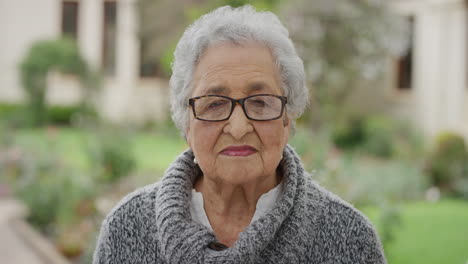 Retrato-De-Una-Anciana-Jubilada-En-Un-Jardín-Soleado-Mirando-Pensativo-A-La-Cámara