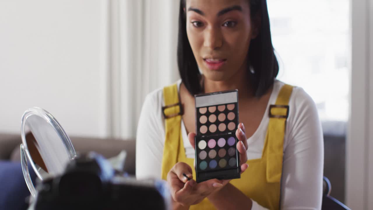 vlogger de género fluido de raza mixta grabando un vlog de maquillaje en casa