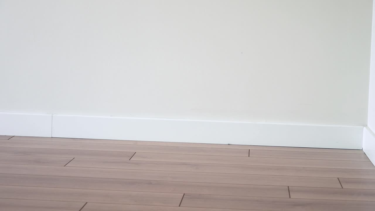 Empty Room Corner with Wood Flooring and White Baseboard