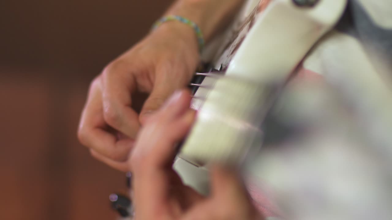 cierre de un músico profesional tocando melodías en una guitarra eléctrica con una púa de guitarra durante una sesión en vivo con cálidas luces de estudio y un amplificador en el fondo borroso