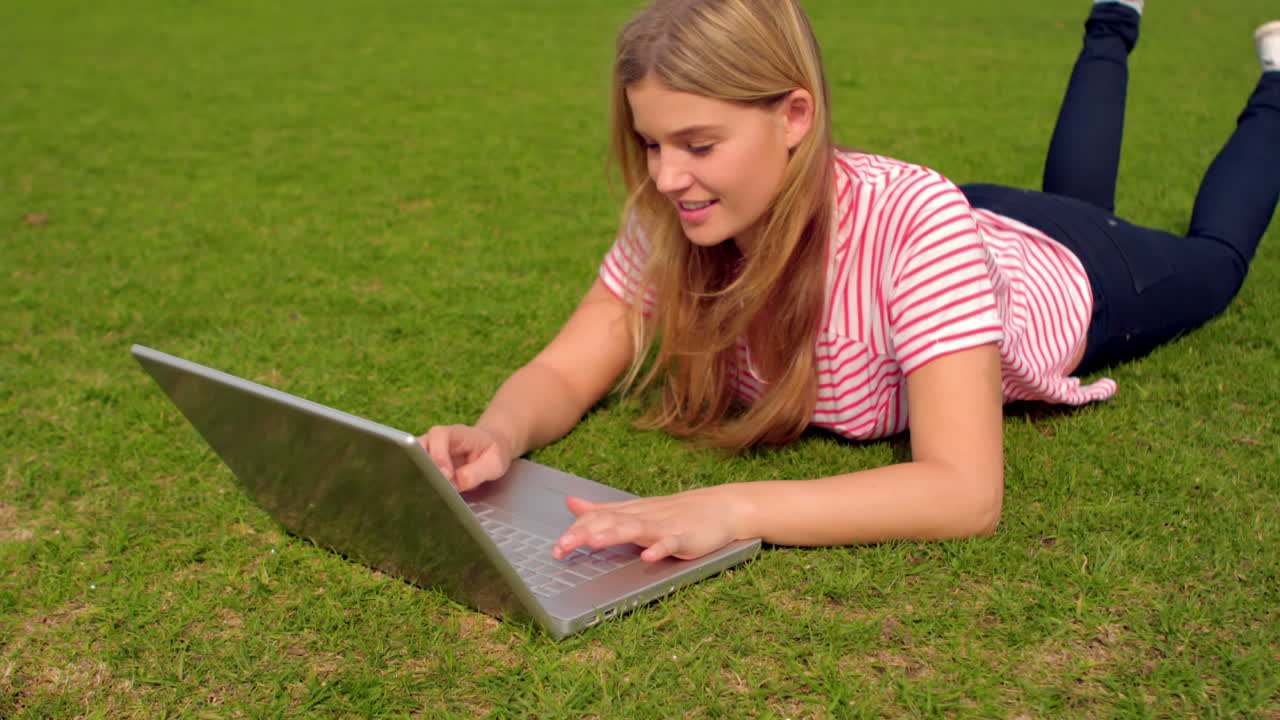 mujer sonriente usando una computadora portátil en el parque