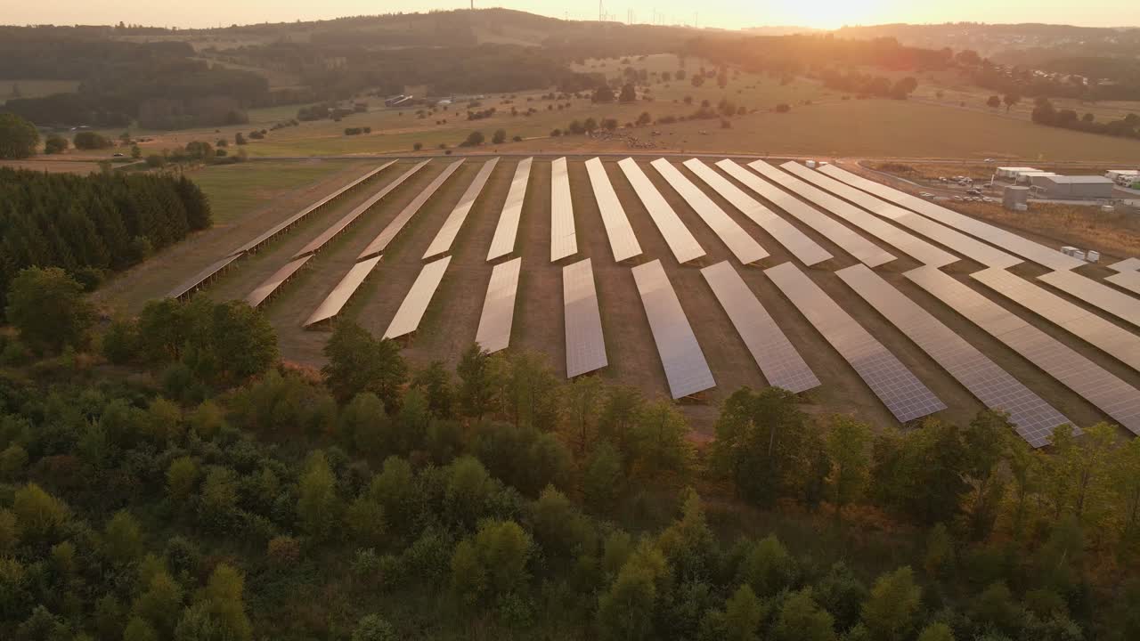 Nærbillede set fra siden af et solcellefelt, hvor solnedgangen reflekteres i panelerne