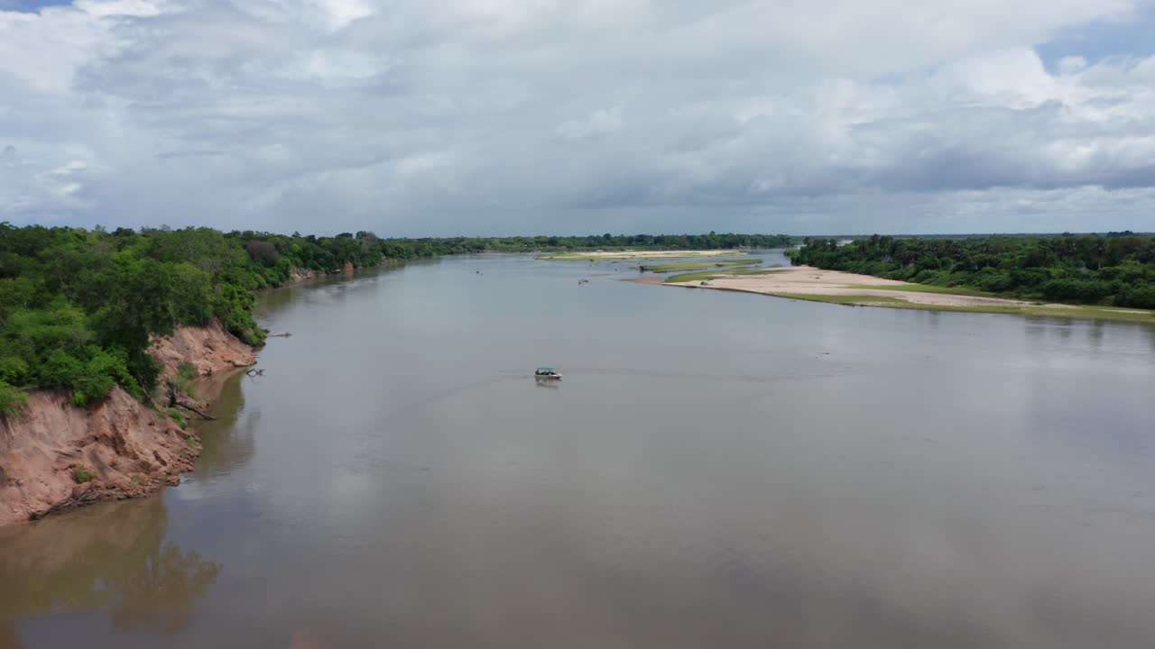 Aerial drone shot flying backwards away from a boat standing still on a river in Selous, Tanzania