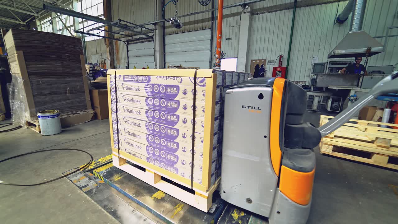 Forklift among the materials in the hangar. Warehousing of wooden slabs