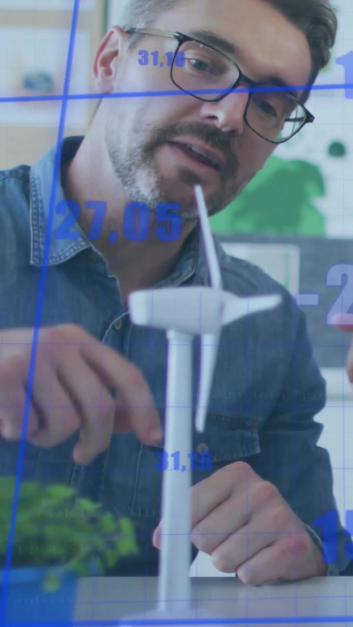 Vertical video: Man speaking, energy charts overlaying while rotating turbine blade for review