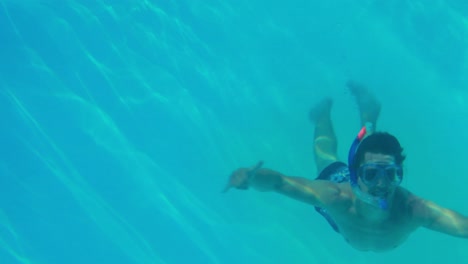 happy man diving into swimming pool wearing a snorkel