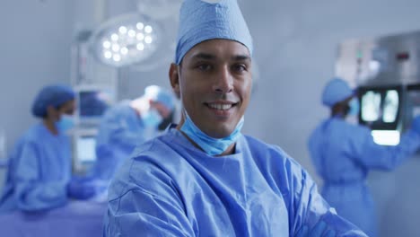 retrato de un cirujano de raza mixta de pie en la sala de operaciones sonriendo a la cámara