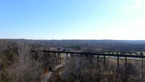 disparo aéreo empujando sobre un bosque hacia el papa lick trestle en louisville kentucky en una tarde soleada