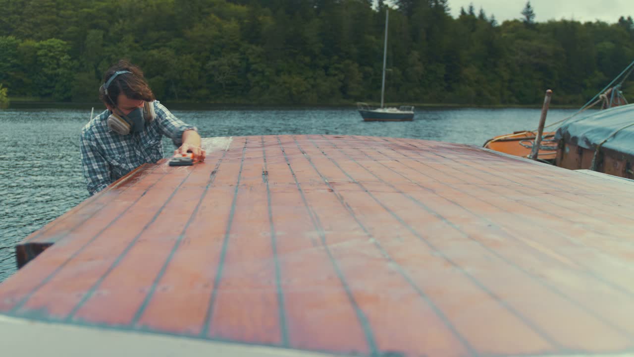 joven carpintero caucásico lijado a mano timonera techo de cabina de barco de madera
