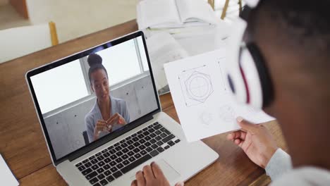 African-american-businessman-sitting-at-desk-using-laptop-having-video-call-with-female-colleague