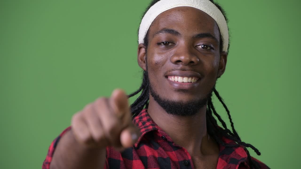 Ung flot afrikansk mand med dreadlocks mod grøn baggrund