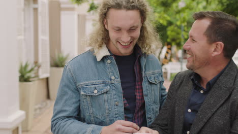 portrait of two attractive men browsing using smartphone laughing cheerful enjoying silly fun male friends hanging out in urban city