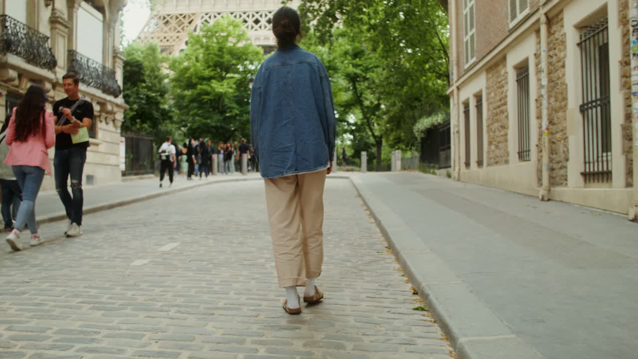 una mujer caminando en parís cerca de la torre eiffel.