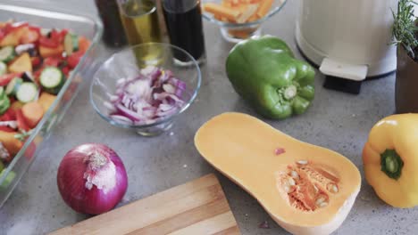 Close-up-of-vegetables,-herbs-and-compost-bin-on-worktop-in-kitchen,-slow-motion