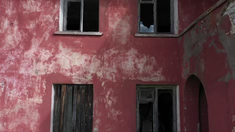 Cerrar-La-Inclinación-Para-Subir-El-Video-De-Un-Dron-De-Una-Vieja-Casa-Roja-Abandonada-Con-Una-Pared-Roja-Y-Ventanas-Rotas