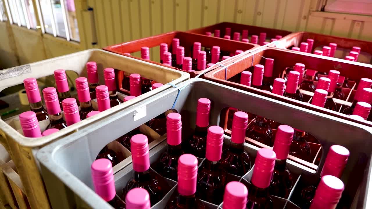 Crates of Red Wine Bottles with Pink Caps in Vinery Storage Room