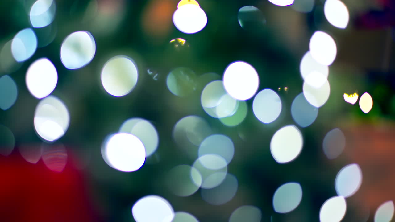 Bright and colorful lights illuminate a Christmas tree, creating a cheerful holiday mood. The scene captures the joy and warmth of the festive season with soft bokeh effects