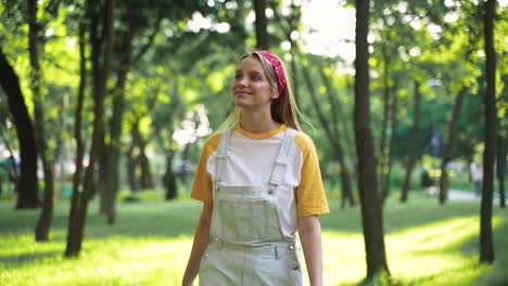 Pretty-Cheerful-Girl-Enjoying-Freedom-And-Walking-Towards-The-Camera-In-A-Green-Park