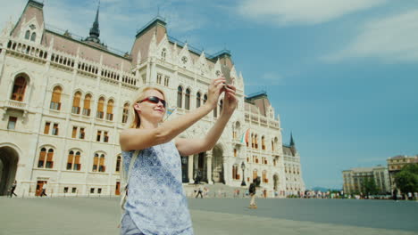 young woman photographes herself against the background of the hungarian parliament in budapest