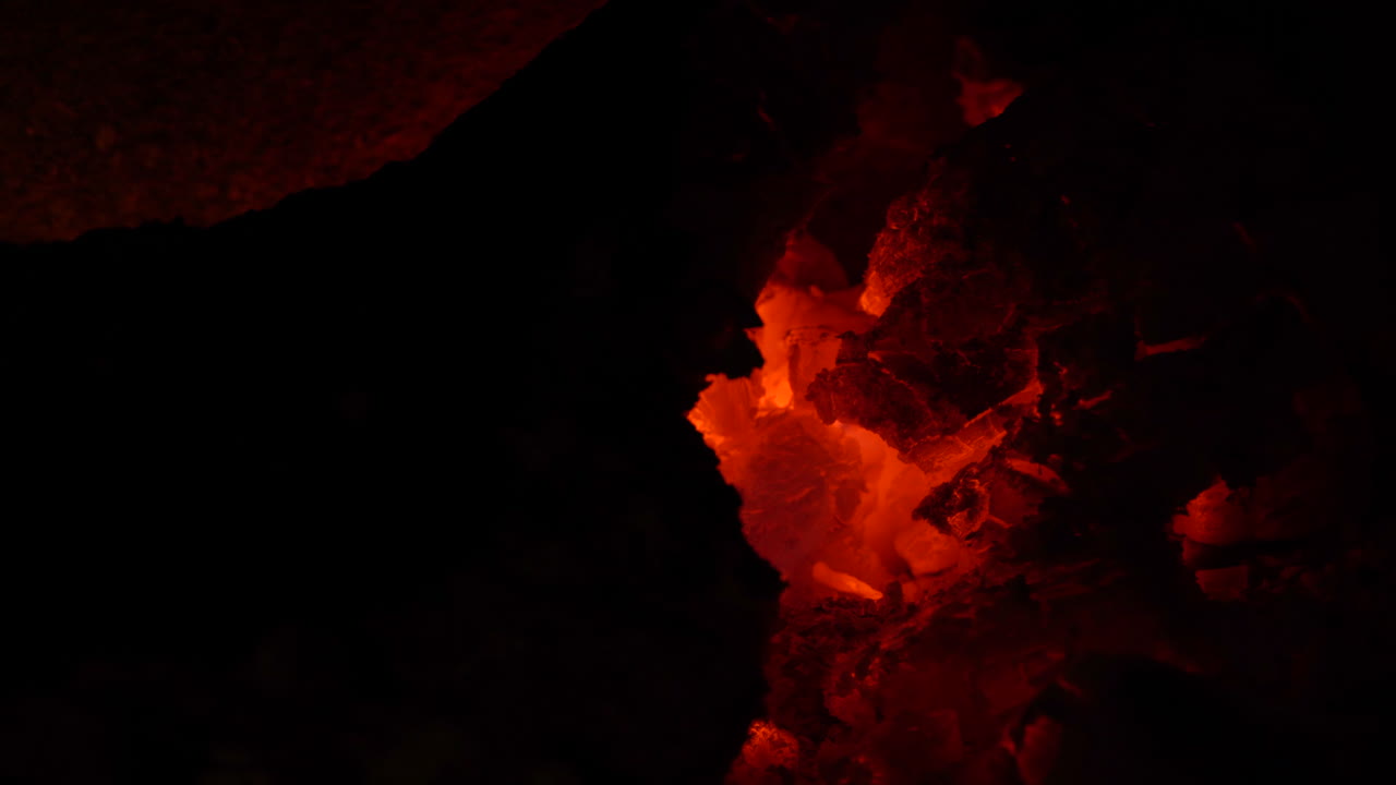 Cosy flaming and glowing fire with little sparks and orange embers.  Close up.