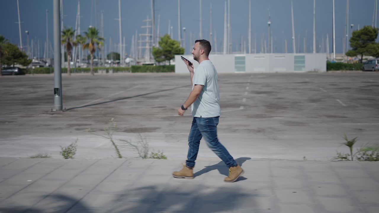 Man Walking and Using Phone by the Marina