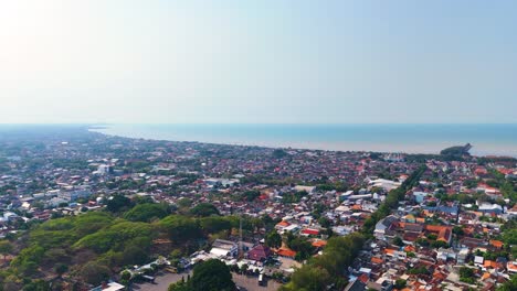 drone shot of tuban regency in east java, indonesia, highlighting the cityscape with its blend of urban and natural landscapes and beach. the java sea is in the background.