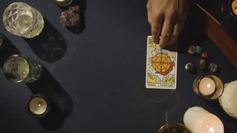 toma aérea de una persona que da una lectura de cartas del tarot colocando la rueda de la fortuna en la mesa