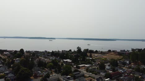 Drone-shot-of-ships-on-the-Puget-Sound-floating-past-a-Seattle-neighborhood