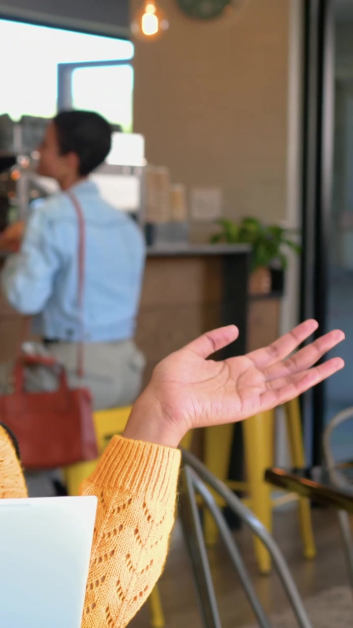 Video verticale: Panoramica su un cliente in camicia blu che sorseggia un caffè e gesticola per ordinare in un bar.