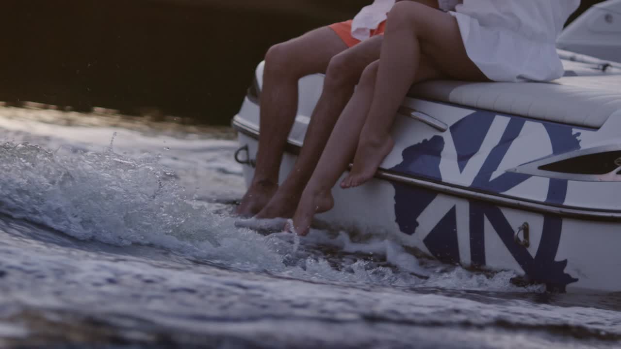 Gambe di uomo e donna in acqua spumeggiante. Gita in barca sul fiume di sera.