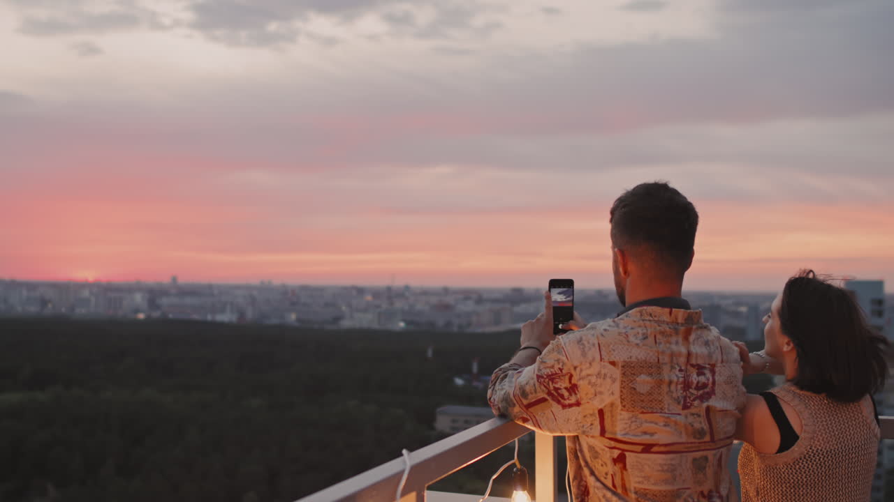 Man Photographing Sunset on Rooftop Terrace