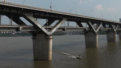 Motorboat-dragging-a-man-doing-waterski-at-Hangang-river-under-Cheongdam-Bridge-in-Seoul,-South-Korea