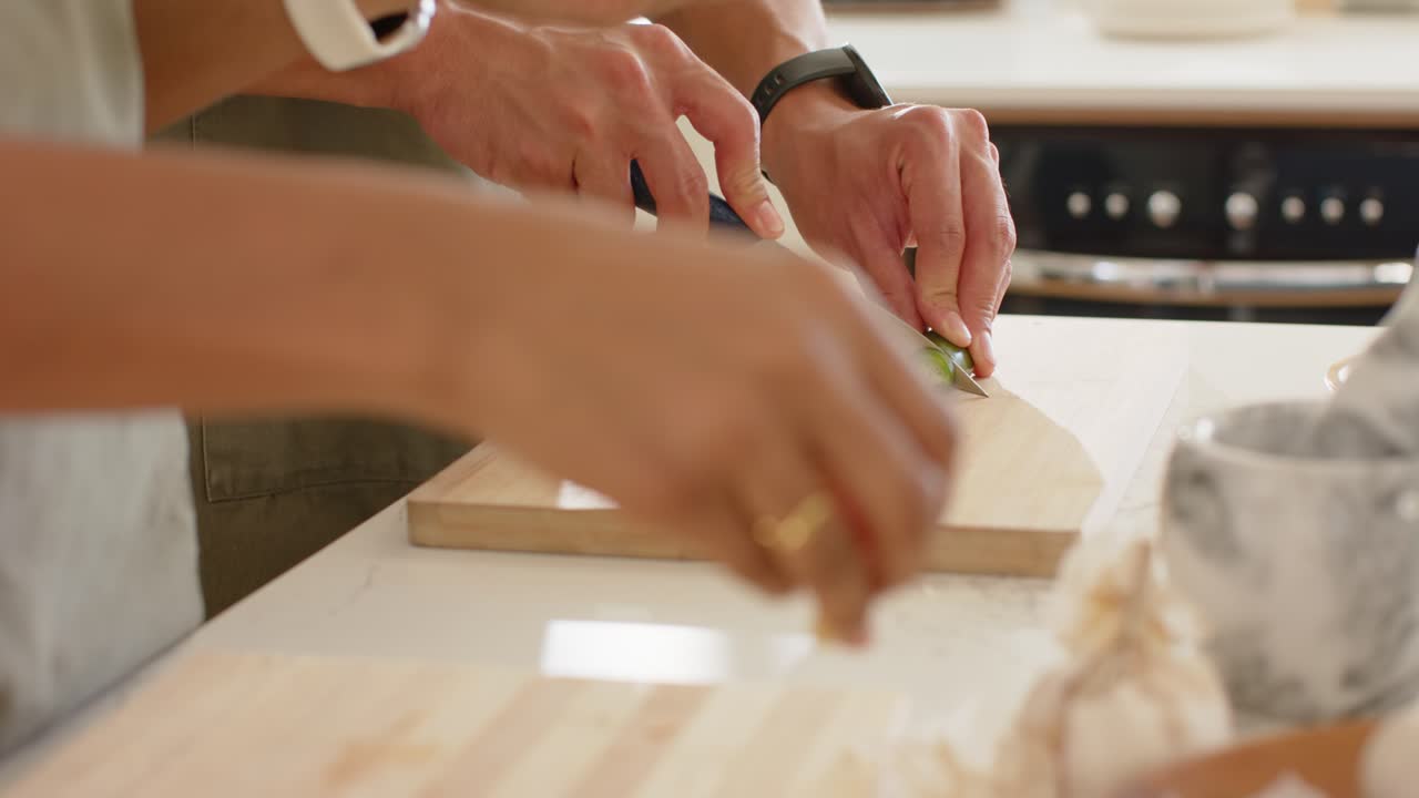 La punta del coltello tocca una verdura verde; si tagliano fette rotonde su un tagliere di legno per la preparazione del pasto.