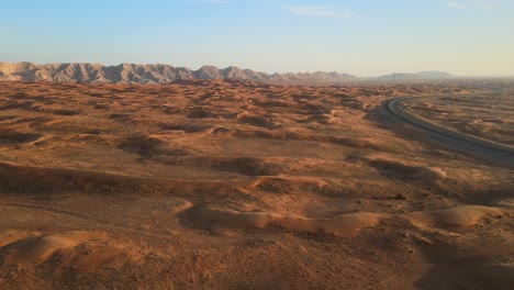 Aerial-drone-view-of-the-Arabian-Desert,-The-land-is-transforming-from-desert-to-green,-Mleiha-mountains-in-the-background,-Sharjah,-United-Arab-Emirates