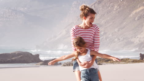 mother and daughter on summer vacation playing on beach together