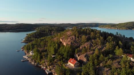 aerial: beautiful fishing cabins on norwegian fjord islet, sunset panoramic